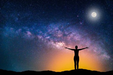 Samanyolu Gökadası ile manzara. Gece gökyüzünde yıldız, ay ve siluet mutlu kadın dağ. 