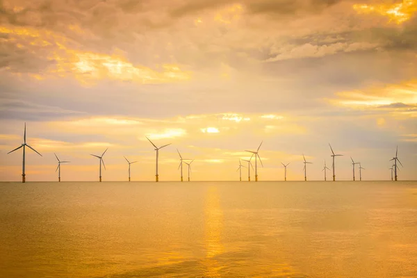 Sunset Offshore Wind Turbine in a Wind farm under construction off coast of England.