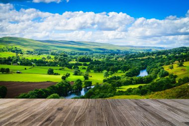 Meandering River making its way through lush green rural farmland in the warm early sunlight with wooden walkway. clipart