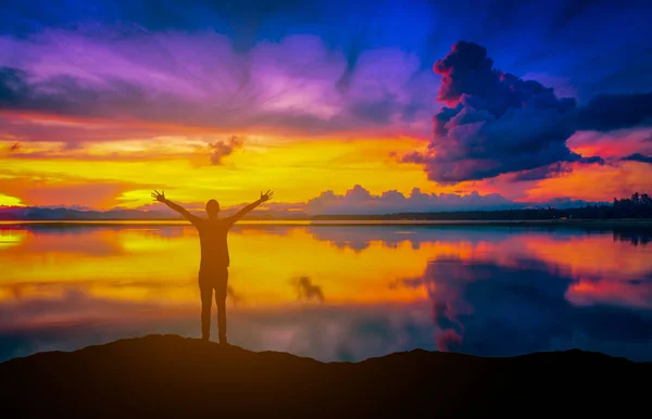 Gambar pemandangan Dramatic sunset di atas laut dengan siluet pria bahagia di gunung . — Stok Foto