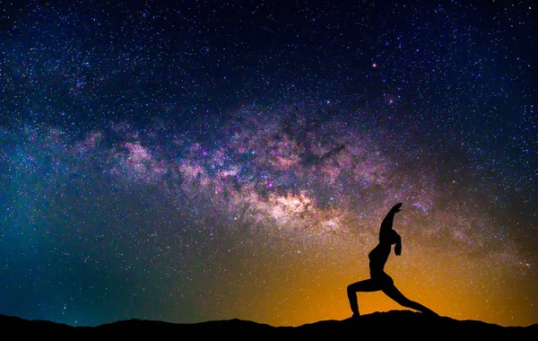 Landschaft mit Milchstraßengalaxie. Nachthimmel mit Sternen und Silhouette Frau praktiziert Yoga auf dem Berg. — Stockfoto