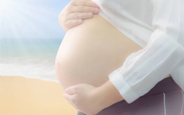 Zwangere vrouw staat op het strand — Stockfoto
