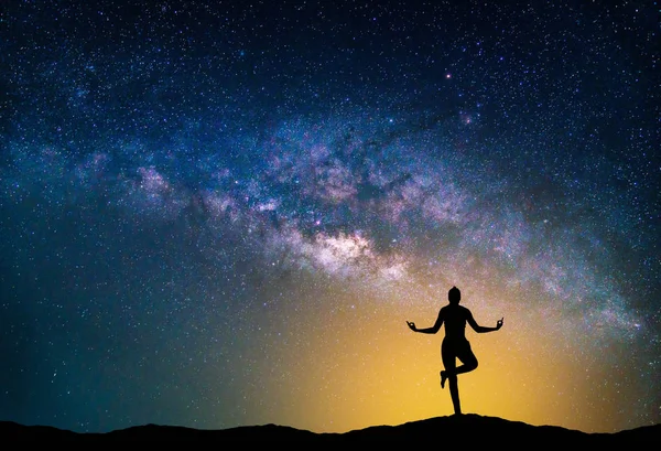 Пейзаж с галактикой Млечный Путь. Ночное небо со звездами и женщиной-силуэтом практикующей йогу на горе . — стоковое фото