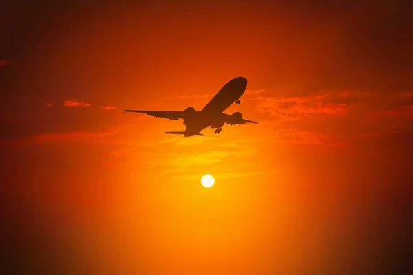 Silueta de avión volar en el cielo durante la puesta del sol . — Foto de Stock