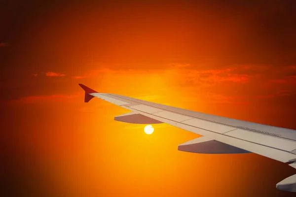 Silhouette of wing plane fly on sky during sunset.