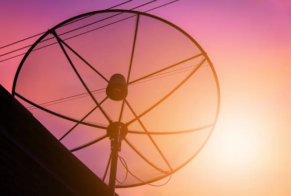 Silhouette satellite dish communication technology network on building roof at sunset. — Stock Photo, Image