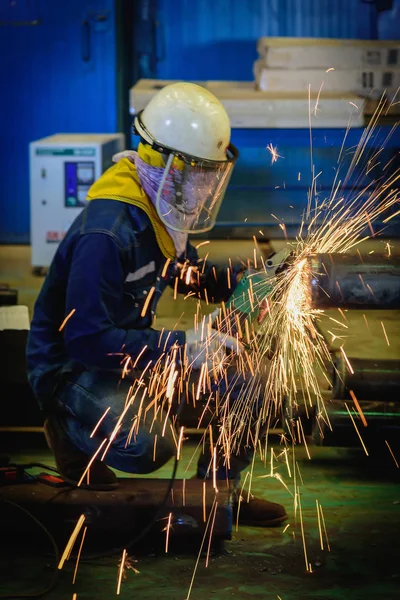 Trabajador industrial pesado utiliza molienda de rueda eléctrica en tubería de acero en la fábrica de acero con chispas . — Foto de Stock
