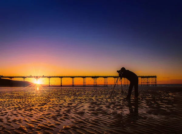Silhouette d'un photographe sur un magnifique coucher de soleil ou lever de soleil au quai Saltburn by the Sea, North Yorkshire Royaume-Uni . — Photo