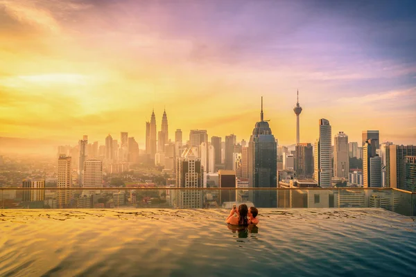Reiziger paar vrouw in zwembad op het dak van hotel bij zonsopgang in Kuala Lumpur, Maleisië. — Stockfoto