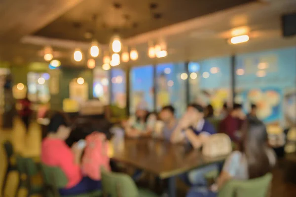 Imagen borrosa de la cafetería y la gente se sienta en la mesa con fondo bokeh . — Foto de Stock