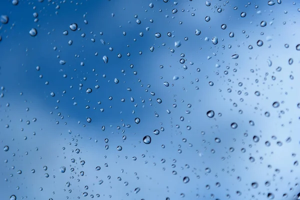 Gotas de lluvia en el cristal de una ventana. Profundidad de campo superficial. Enfoque selectivo. Tonalidad azul — Foto de Stock