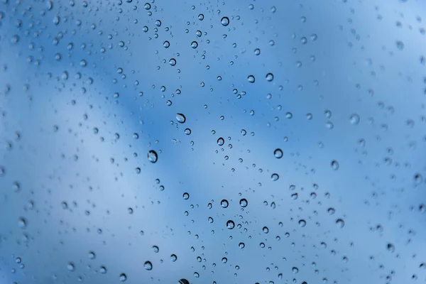 Gotas de lluvia en el cristal de una ventana. Profundidad de campo superficial. Enfoque selectivo. Tonalidad azul — Foto de Stock