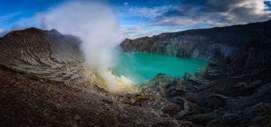 Kawah Ijen volcano with green lake on blue sky background at morning in East Java, Indonesia. clipart