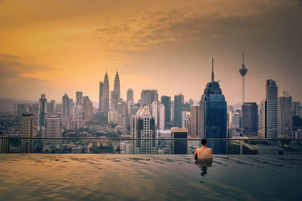 Traveler man looking view skyline Kuala Lumpur città in piscina sul tetto dell'hotel all'alba a Kuala Lumpur, Malesia . — Foto Stock