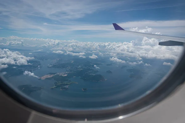 Ala de avión volando sobre el fondo de la ciudad de Hong Kong a través de —  Fotos de Stock
