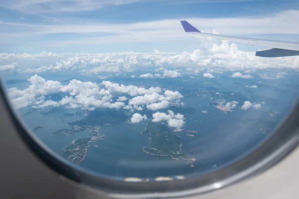 Ala de avión volando sobre el fondo de la ciudad de Hong Kong a través de — Foto de Stock