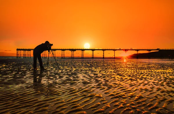 美しい夕日の上の写真家のシルエット桟橋でソルトバーン ノースヨークシャー英国 — ストック写真