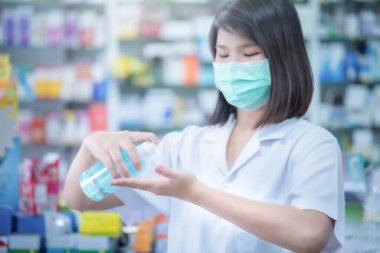 Asyalı kadın doktor, cerrahi maske takıyor. Alkol pompası kullanıyor. Geçmişi bulanık..