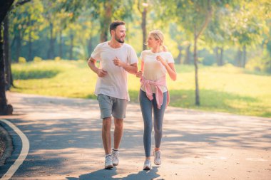 Gün batımında parkta koşan genç bir çiftin portresi. Spor ve aşk kavramı. Sıcak ton.