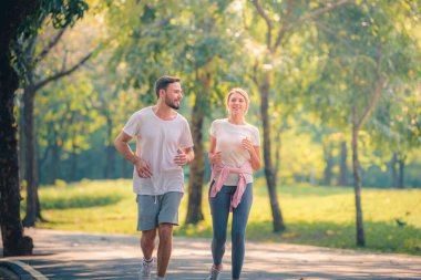 Gün batımında parkta koşan genç bir çiftin portresi. Spor ve aşk kavramı. Sıcak ton.