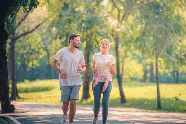 Portrait of Young couple running in the park at sunset. Concept sport and love. Warm tone.