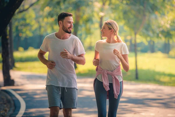 Gün batımında parkta koşan genç bir çiftin portresi. Spor ve aşk kavramı. Sıcak ton.