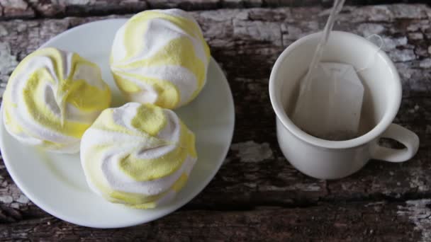 Marshmallows e uma xícara branca com chá preto — Vídeo de Stock