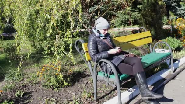 Vrouw geniet van zonlicht op een bankje in de herfst — Stockvideo