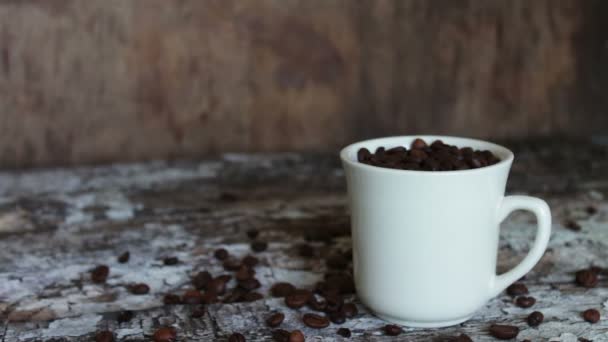 Taza blanca llena de granos de café de cerca — Vídeo de stock