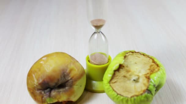 Withered old rotten apples next to running hourglass — Stock Video