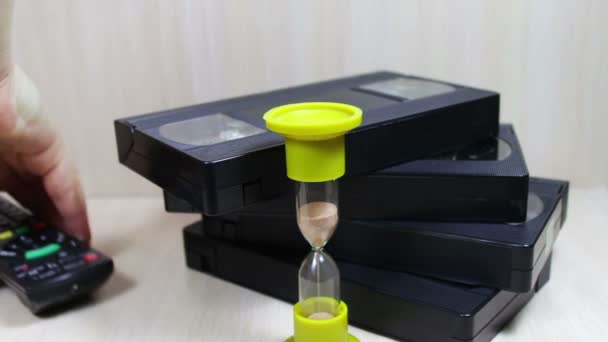 Pila de cinta de vídeo VHS casete y reloj de arena — Vídeo de stock