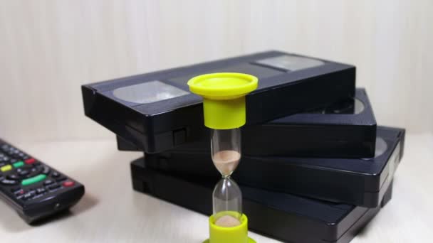 Stack of VHS video tape cassette and hourglass — Stock Video