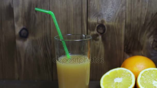 Sinaasappelsap in een glas en vers fruit op houten achtergrond — Stockvideo