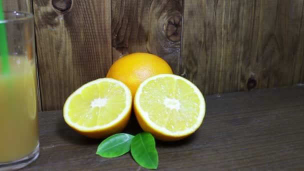 Apelsinjuice i ett glas och färsk frukt på trä bakgrund — Stockvideo