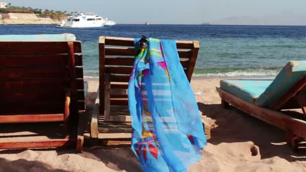 Houten stoel op het strand van achtergrond van blauwe zee en witte jacht drijft — Stockvideo