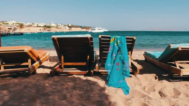 Sedia di legno sulla spiaggia di sfondo di blu del mare e bianco yacht galleggia — Video Stock