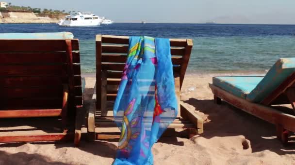 Houten stoel op het strand van achtergrond van blauwe zee en witte jacht drijft — Stockvideo