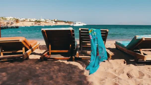 Деревянный стул на пляже на фоне синего моря и белых яхт плавает — стоковое видео