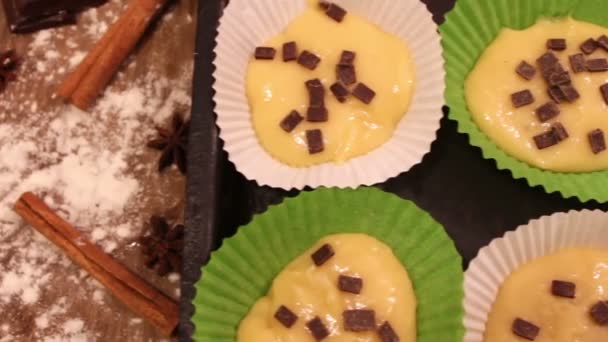 Raw dough for muffins in special paper baking dish sprinkled with chocolate pieces — Stock Video