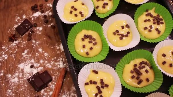 Masa cruda para magdalenas en un plato especial para hornear de papel espolvoreado con trozos de chocolate — Vídeo de stock