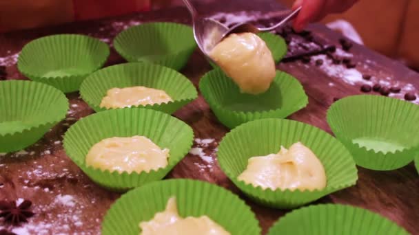 La mano femminile mette la pasta cruda per muffin in bicchieri di carta — Video Stock