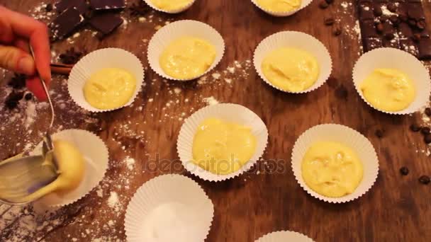 Vrouwelijke hand zet Raw deeg voor muffins in papier keukengerei — Stockvideo