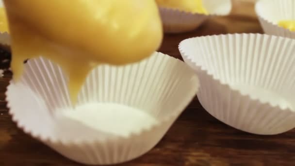 Kvinnlig hand sätter rå deg för muffins i papper bakeware — Stockvideo