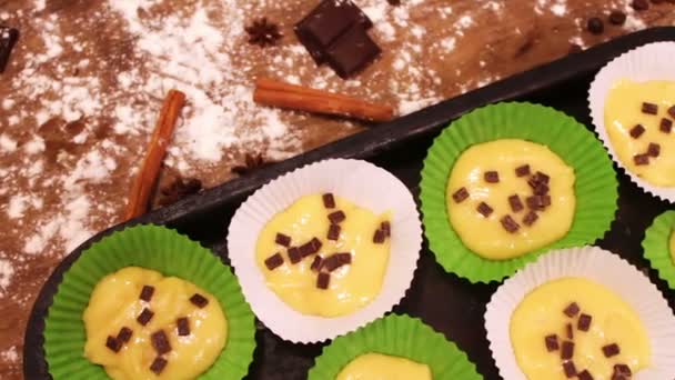 Ruwe deeg voor muffins in speciaal papier bakken schotel besprenkeld met chocoladestukjes — Stockvideo