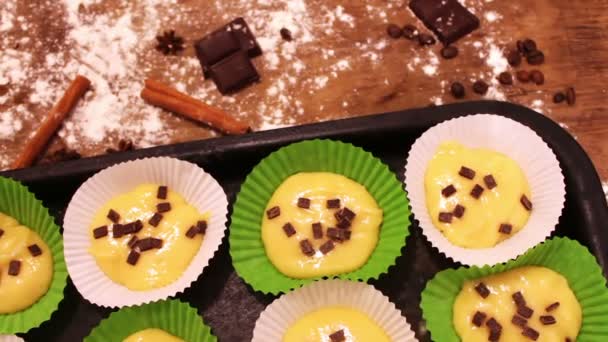 Сире тісто для кексів у спеціальній паперовій випічці, посипане шоколадними шматочками — стокове відео