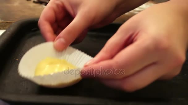 Женщины руки положить на выпечку свежее тесто для кексов в бумажной выпечки блюдо вблизи зрения — стоковое видео