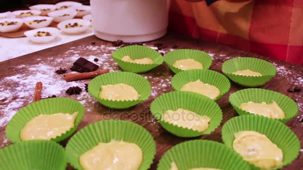 Mano femenina pone masa cruda para magdalenas en el bakeware de papel — Vídeos de Stock