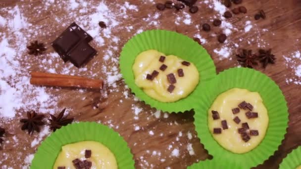 Masa cruda para magdalenas en un plato especial para hornear de papel espolvoreado con trozos de chocolate — Vídeo de stock