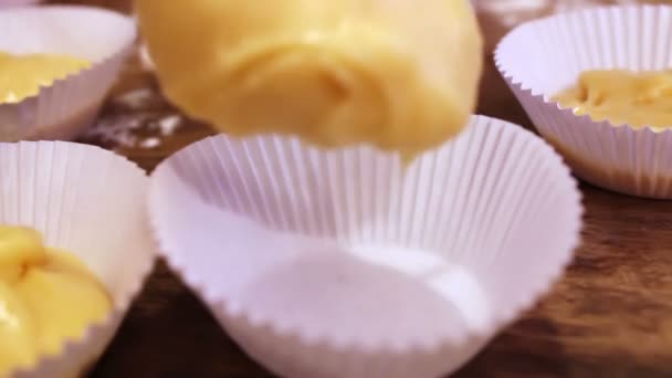 Mano femenina pone masa cruda para magdalenas en el bakeware de papel — Vídeos de Stock