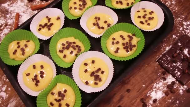 Masa cruda para magdalenas en un plato especial para hornear de papel espolvoreado con trozos de chocolate — Vídeo de stock